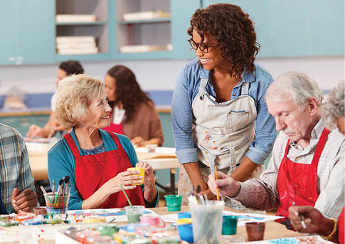 Group Of Retired Seniors Attending Art Class In Community Centre With Teacher